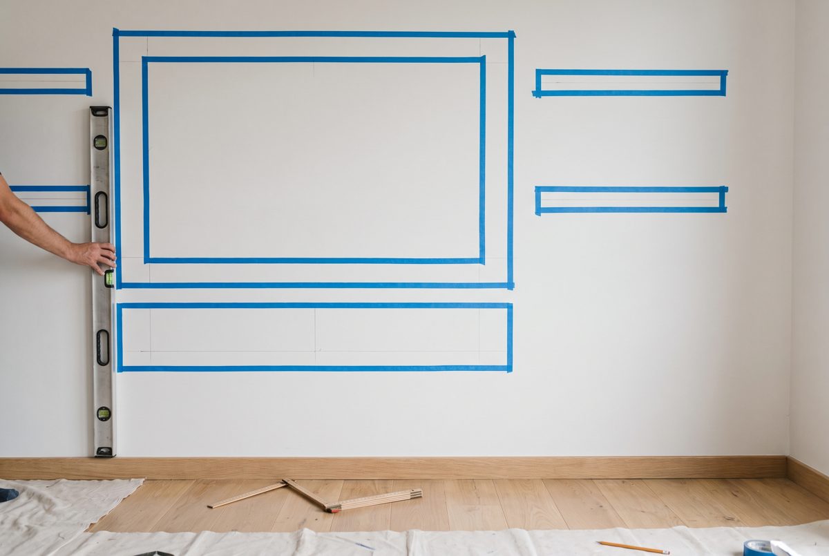 Planung der TV-Wand mit Malerkrepp und Wasserwaage an der Wand