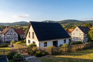 Einfamilienhaus mit Photovoltaikanlage auf dem Dach zwischen Fachwerkhäusern in einem hessischen Dorf