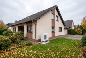 Einfamilienhaus aus den 1970er-Jahren in Nordrhein-Westfalen mit Außeneinheit einer Luft-Wasser-Wärmepumpe im Garten